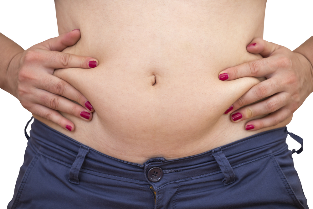 Close-up of a woman's abdomen highlighting areas of unwanted body fat suitable for Emsculpt treatment.